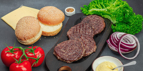 Grilled burger patties. Hot beef cutlets, buns, vegetables and sauce. Homemade American classic