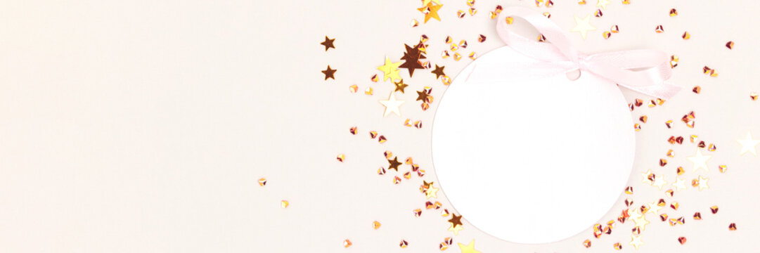 Banner with round empty tag with tied ribbon bow. Gold coored stars confetti on a gray background.