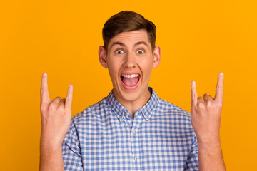 Photo of excited man over yellow backgroud making rock gesture punk concert entertainment