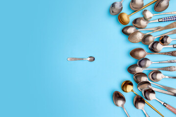 Tips of cutlery. Top view photo one coffee spoon surrounded of variety of antique silverware and...