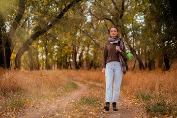 Fototapeta premium woman walking in the forest, female traveler walking through the forest on a sunny autumn day, young Caucasian woman hiking, girl with a tourist backpack walking in the forest
