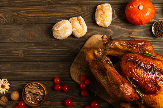 thanksgiving turkey and freshly baked bread near cherry tomatoes and pumpkin on rustic wooden table
