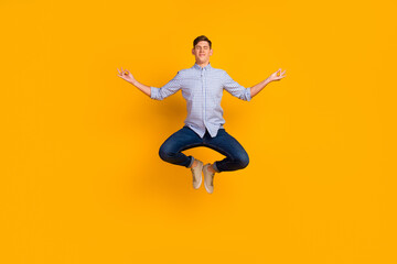 Full length photo of attractive meditating guy jumping up new asana isolated over yellow color background