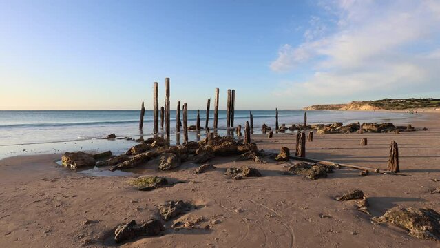 Rock and wooden structure of old jetty on the beach.