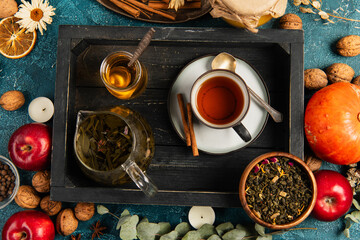 Fototapeta na wymiar thanksgiving concept, black wooden tray with herbal tea and honey near colorful harvest objects