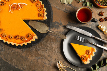 thanksgiving pumpkin pie with walnuts and orange slices near vintage cutlery on rustic stone table