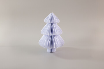 a paper christmas tree sitting on top of a table, folk art, grey background