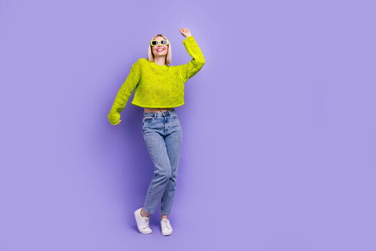 Full length photo of funky sweet lady wear green pullover dark glasses having fun empty space isolated purple color background