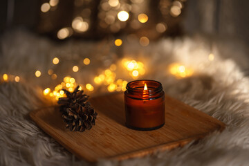christmas still life with candle. new year christmas card. lights of garlands, lighted candle and a...