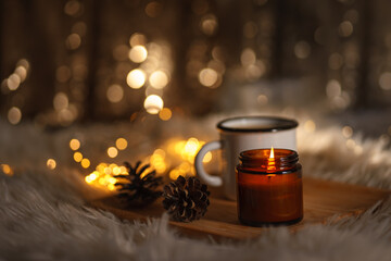 christmas still life with candle. new year christmas card. lights of garlands, lighted candle and a...