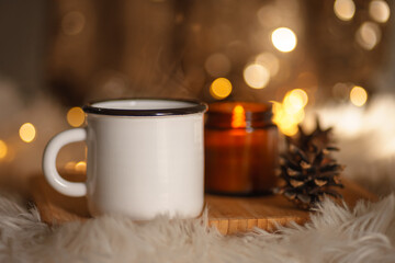 Obraz na płótnie Canvas christmas still life with candle. new year christmas card. lights of garlands, lighted candle and a cup of coffee. comfort and hygge. selective focus. bokeh