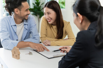 Real estate sales agent explain rental or buying condition to young couple before move to new home or apartment at real estate sales office. Asian urban young couple lifestyle concept.