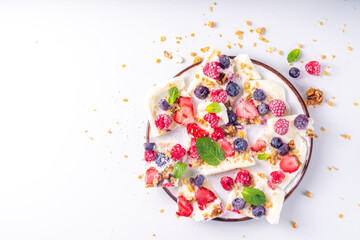 Homemade frozen Yogurt Bark, alternative healthy keto diet ice cream made from greek yogurt, fresh berries, nuts, granola, honey, on baking tray deco. Frozen yoghurt bars with fruit berry toppings