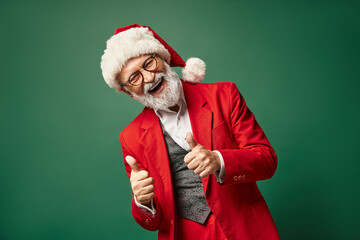 Fototapeta na wymiar happy jolly Santa showing thumbs up gesture and smiling cheerfully at camera, Christmas concept