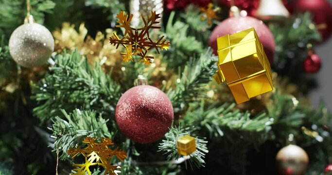 Animation of gold christmas decorations over christmas tree background