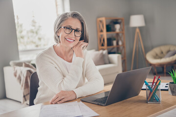 Photo of positive cheerful elderly lady accountant wear white cardigan working modern device...