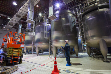 Male worker do  inspection  and record process milk cellar stainless steel factory tanks