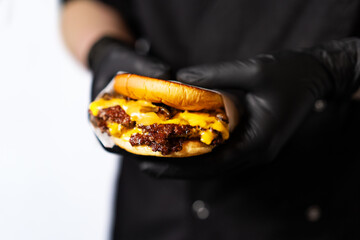 A craft juicy burger with cheese is held in the hands