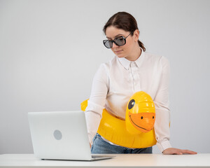 Caucasian woman working at a laptop in sunglasses and in a swimming circle duck. Office worker dreaming of vacation. 