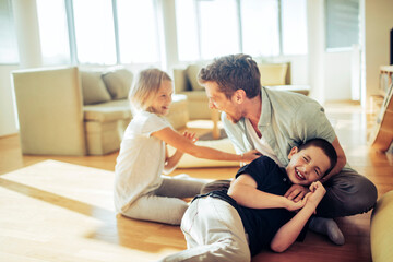 Playful young father having fun with his children in the living room