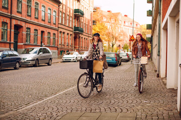 Happy young lesbian riding bikes together in the city