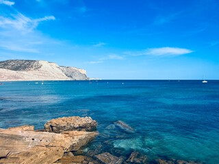 Transparent blue sea water, ocean bay, rocky coast, blue sky