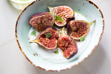 Fresh torn fig fruits served with greek yogurt in a green bowl, horizontal shot, middle close-up