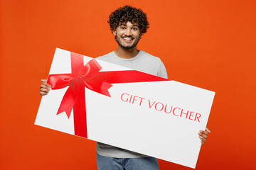 Young smiling happy Indian man he wears t-shirt casual clothes hold big huge gift certificate...