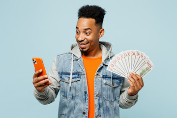 Young man of African American ethnicity wear denim jacket orange t-shirt hold in hand fan of cash...