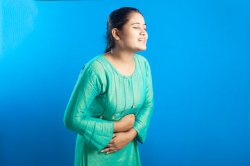 An Indian women suffering from menstrual period pain in blue background