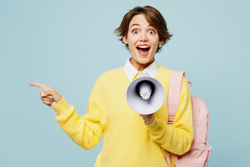 Young amazed woman student wears casual clothes yellow sweater backpack bag hold megaphone scream...