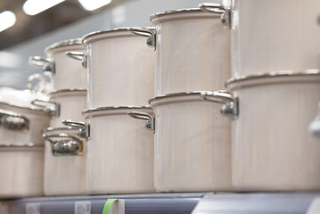 There are a lot of new modern pots made of enameled steel and metal on the shelf. Household goods,...
