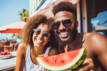 Foto op Canvas A young black couple eats watermelon in a tourist town on vacation. © P