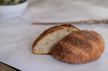 Freshly baked pretty loaf of homemade delicious sourdough bread sliced open on table/counter 