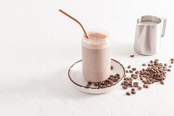 A delicious coffee cappuccino, latte with foam in a modern glass in the form of a beer can stands on a plate among coffee beans. white background