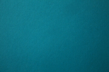Paper background of azure or turquoise color with a slight gradient. Background, texture, selective focus. The texture of designer cardboard in rich blue-green color, paper for art and design. 