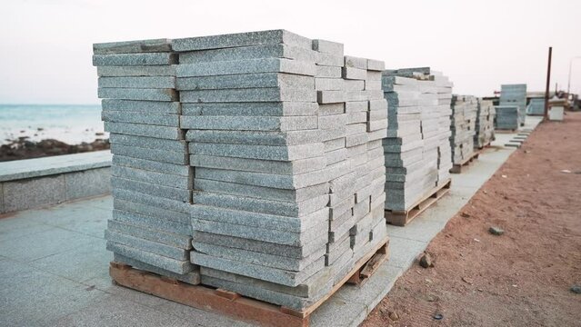 Granite paving slabs planks in a stack on a wooden pallets. Repair of city pedestrian embankment