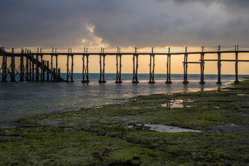 Naklejka premium Wooden walkway stretching over the sea at sunrise, Nungwi, Zanzibar, Tanzania
