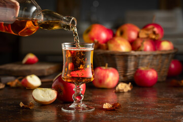 Apple cider is poured from a bottle into a glass.
