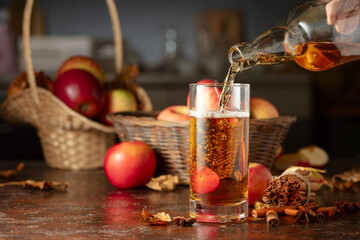 Apple cider is poured from a bottle into a glass.