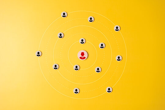 Human resource management and recruitment business concept. Hand holding wood label among candidate icons on yellow background. Select people for recruiting or finding unemployed persons to join work.