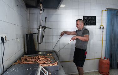 Cocinero friendo masa con dos palos de Churrero para hacer los churros. Los churros son un dulce frito tradicional español.