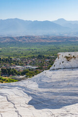 Green fertile agriculture land behind the chalk white geological heritage site of Pamukkale