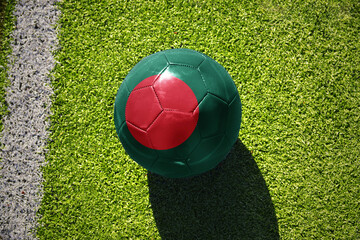 football ball with the flag of bangladesh on the green field near the white line
