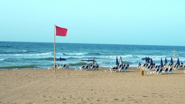 Drapeau rouge dans une plage alg&eacute;riennes, Mer agit&eacute;e, avec parasols et transats 