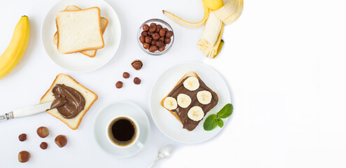 Breakfast with chocolate cream bread, banana and coffee on the white background. Copy space. Top view.