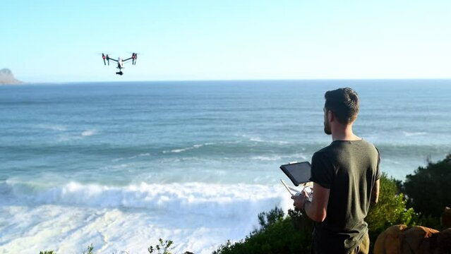 Sky, technology and a man flying a drone over the ocean in nature for video footage during summer. Beach, sea and horizon with a person using a remote to control a robot on the coast by the sea