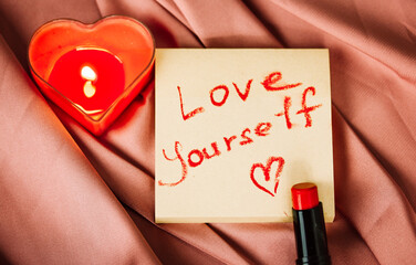 A note to self with a call to love yourself drawing with red lipstick on a silk terracotta cloth...