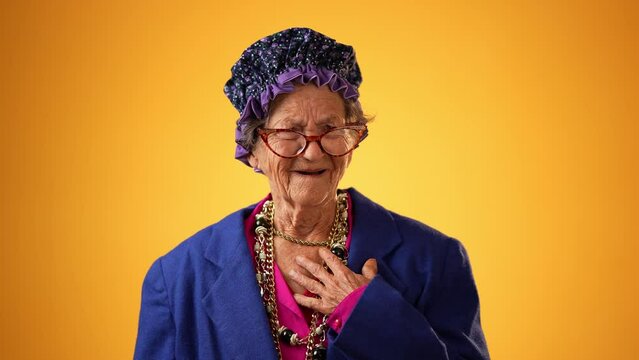 Angry, scared elderly senior old funny crazy woman with wrinkled skin and grey hair put hands out ask WHY ME, isolated on yellow background studio. People emotions