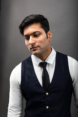 Studio shot of cheerful, young, handsome Indian business man in formal wear against grey background. Corporate male model. Fashion Portrait.